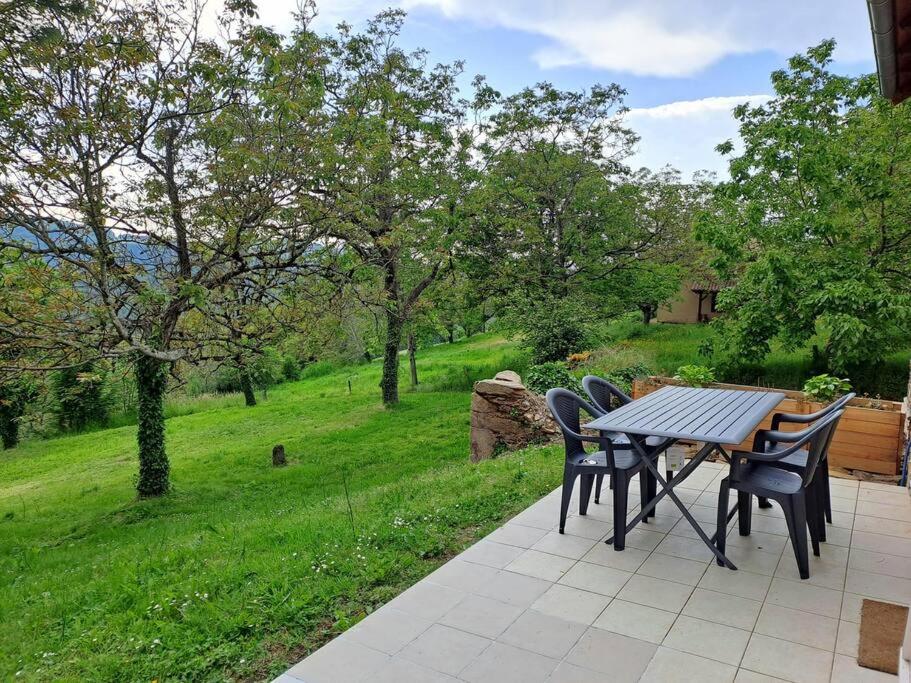 - une table et des chaises sur une terrasse avec vue sur un champ dans l'établissement Maison Landes - Gite 4 personnes, à Latouille-Lentillac