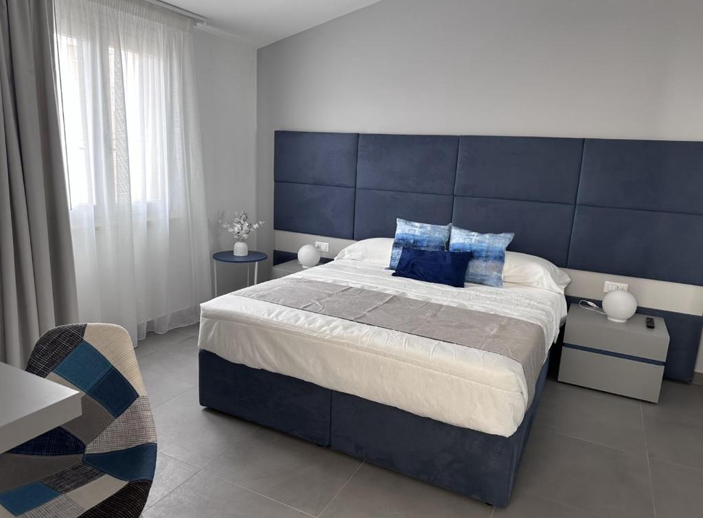 une chambre avec un grand lit avec une tête de lit bleue dans l'établissement Hotel Baia Di Venere, à San Vito Lo Capo