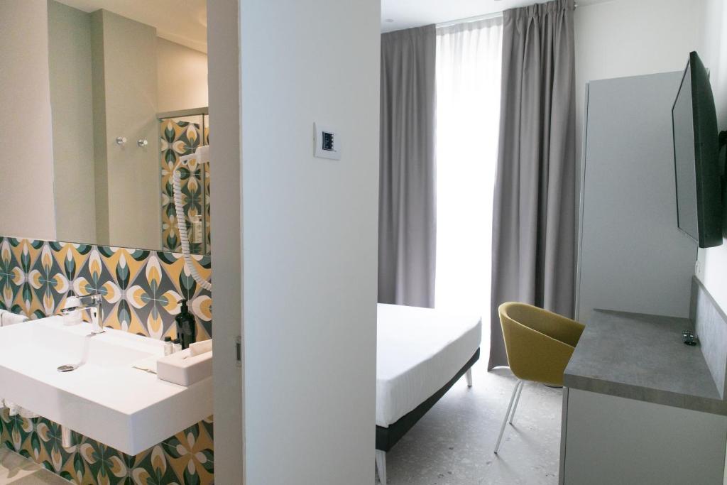 une chambre d'hôtel avec un lavabo et un miroir dans l'établissement Hotel Cristallo, à Senigallia