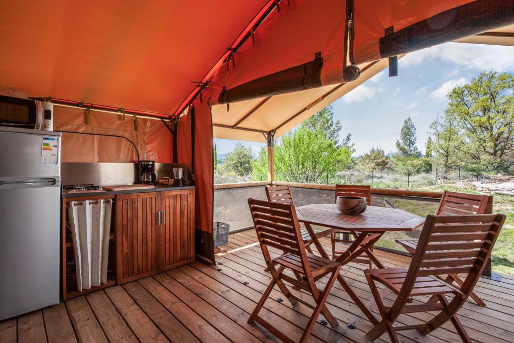 une cuisine et une table sur une terrasse en bois dans l'établissement Le P'tit Gîte Gardéchois, piscine Ardèche - 12pers, à Saint-André-de-Cruzières