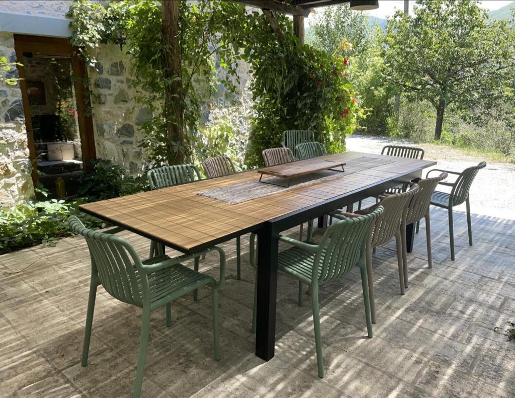 une table et des chaises en bois sur une terrasse dans l'établissement Casale del Pozzo-Villa with pool - Fosdinovo in the borgo of Pulica, à Tendola