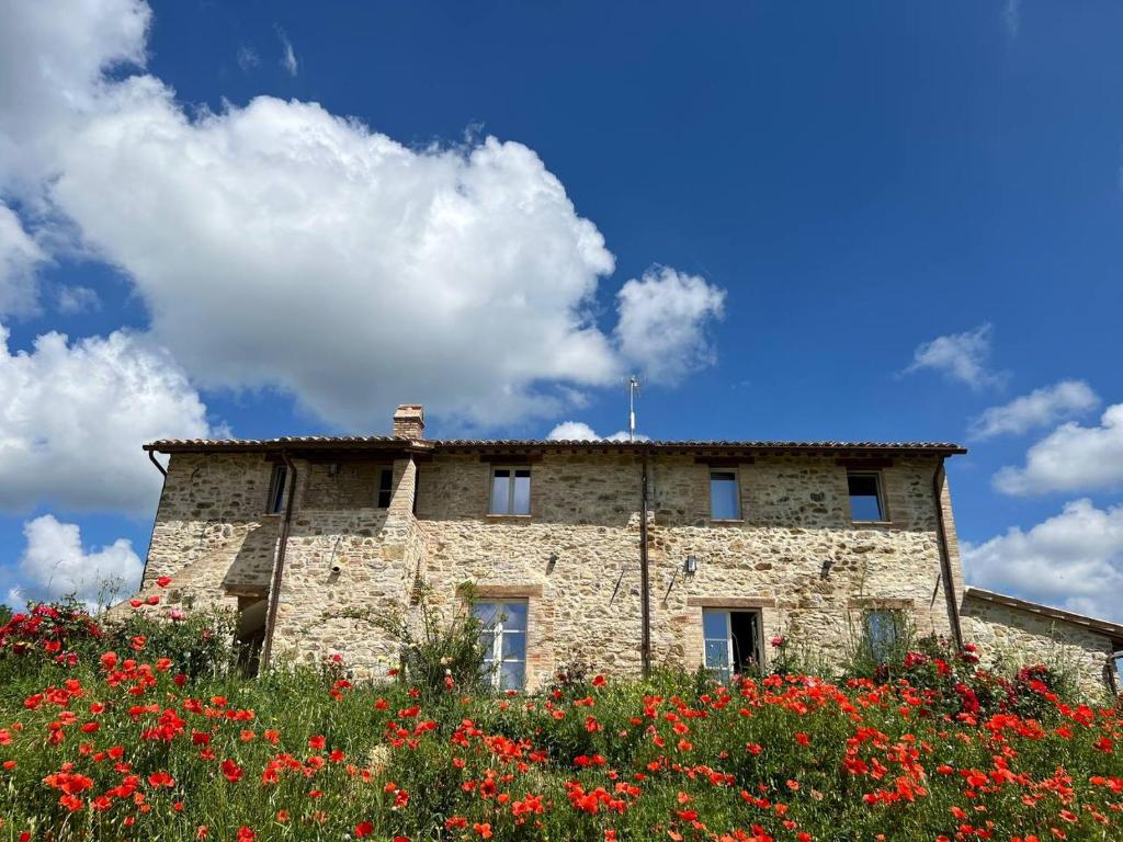 un bâtiment en pierre avec des fleurs rouges devant lui dans l'établissement Banditella, à Orvieto