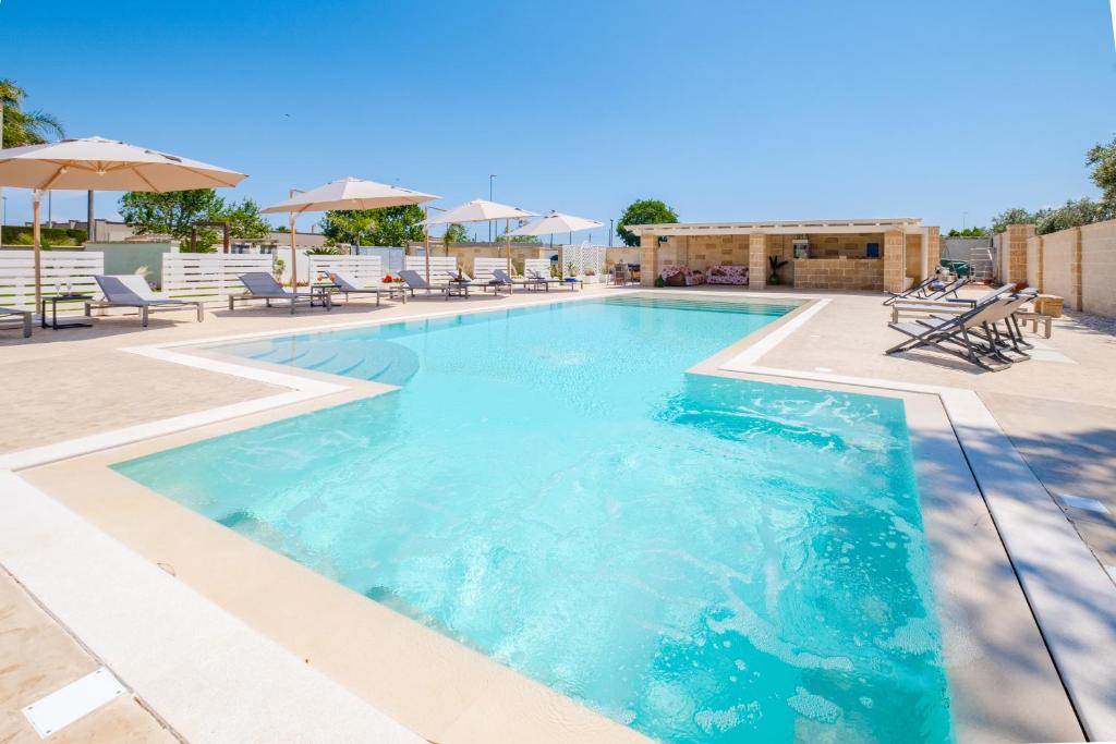 - une piscine d'eau bleue avec des chaises et des parasols dans l'établissement Villa Malea Luxury - Otranto, à Giuggianello