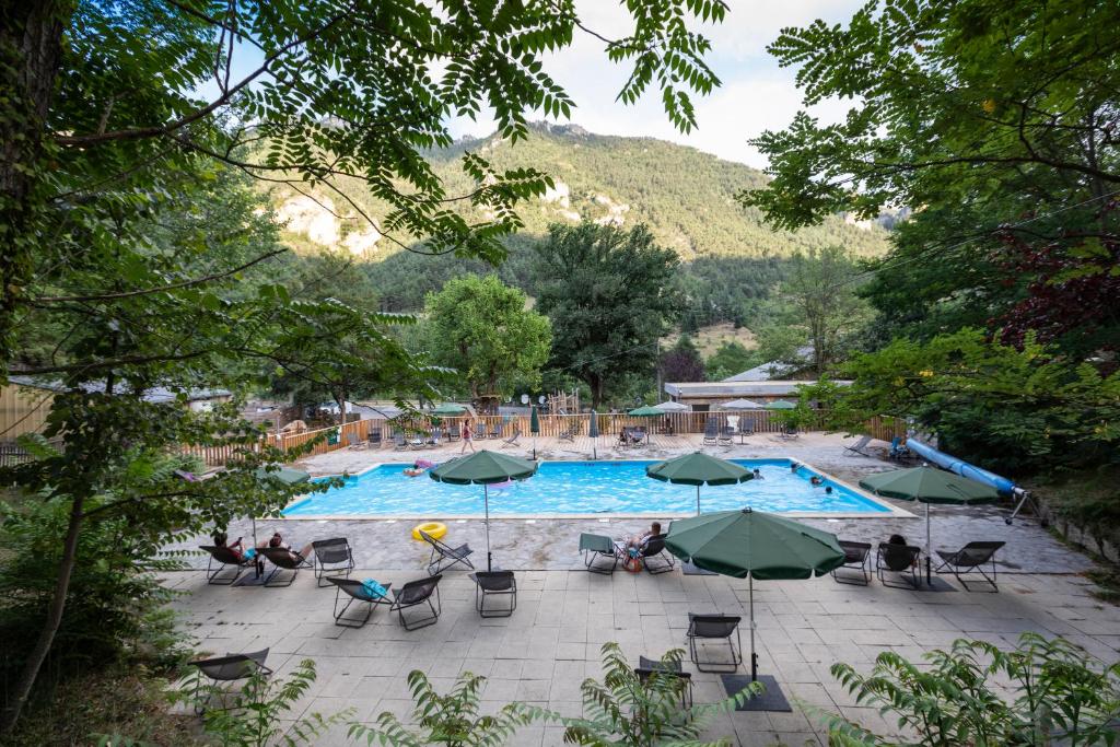 - une piscine avec des chaises longues et des parasols dans l'établissement Huttopia Gorges du Tarn, aux Vignes