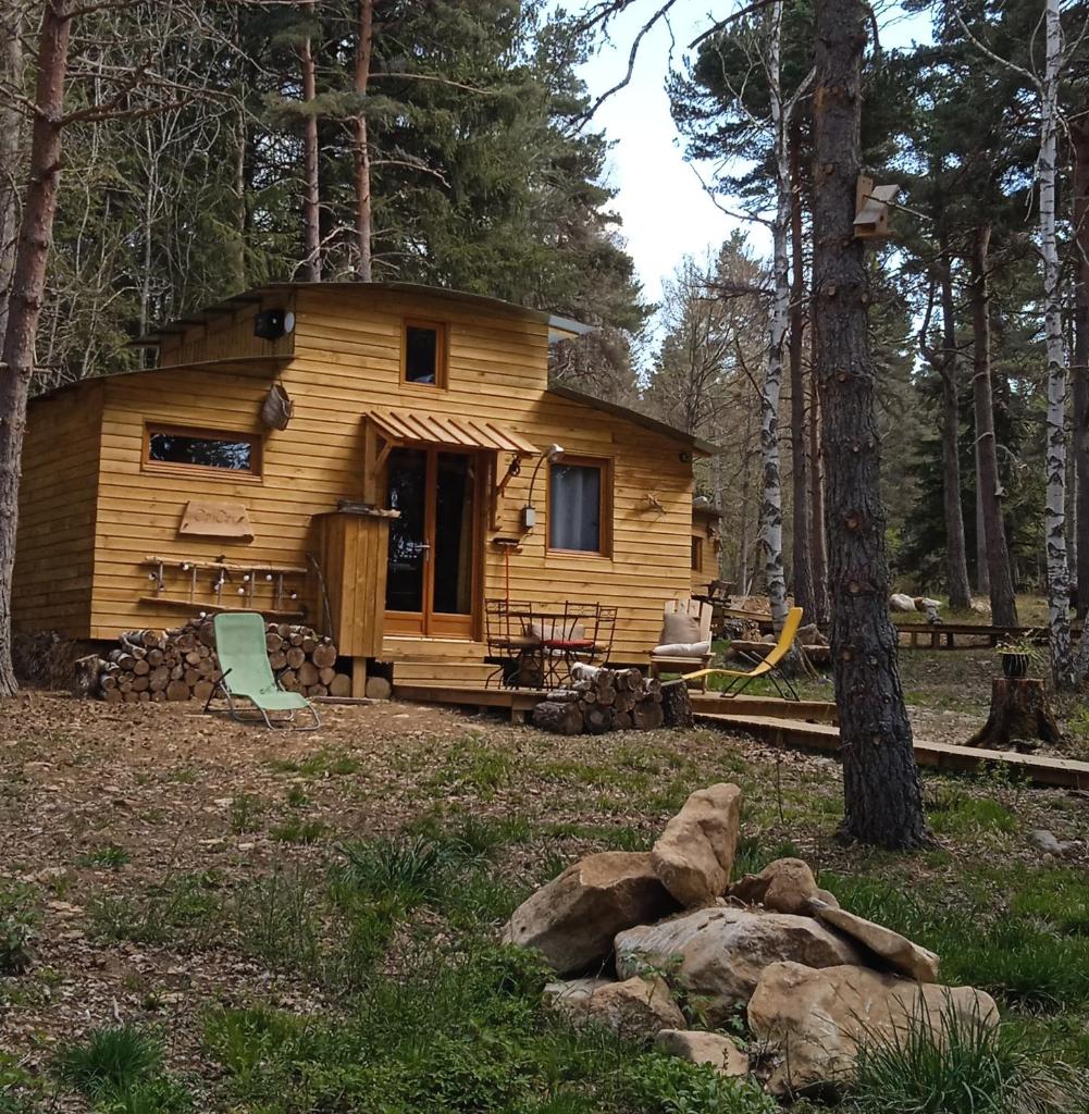 une cabane en rondins dans les bois avec des rochers devant elle dans l'établissement Chalet Cricri Domaine de la Mamounette, à Champclause 12 autres photos