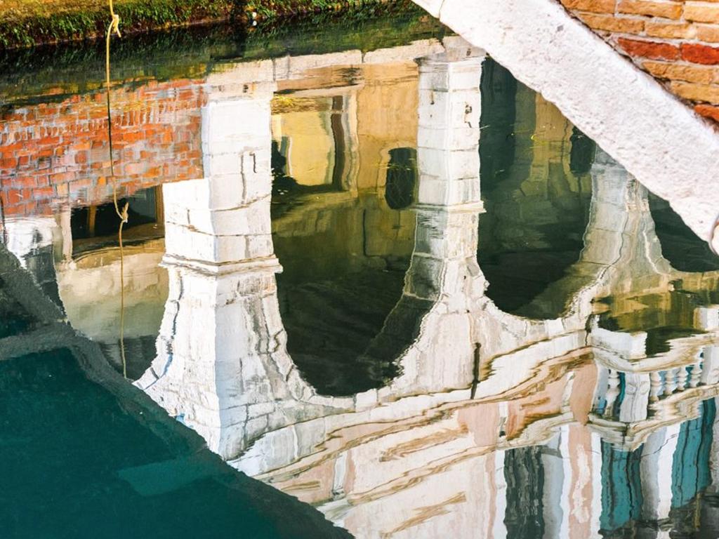 un reflet d'un bâtiment dans un bassin d'eau dans l'établissement Hotel del Mar, à Sottomarina