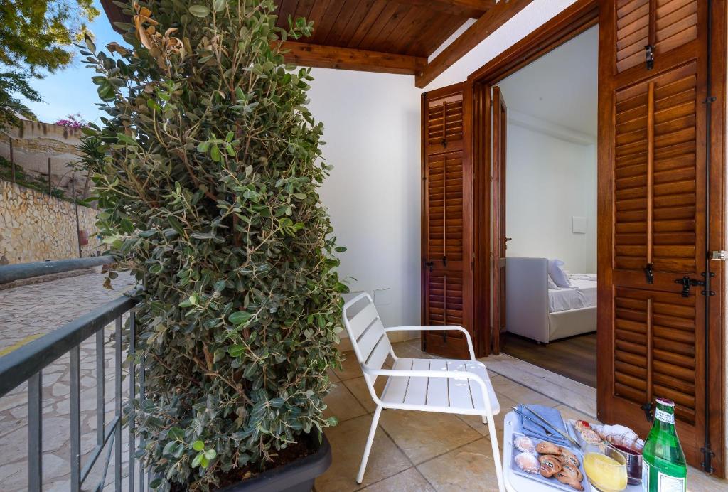 une chaise blanche assise sur un balcon avec une grande plante dans l'établissement Albergo Auralba, à San Vito Lo Capo