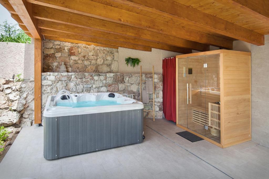 une salle de bain avec un bain à remous à côté d'un mur de pierre dans l'établissement Villa Fani-Wellness & Relax, à Malcesine