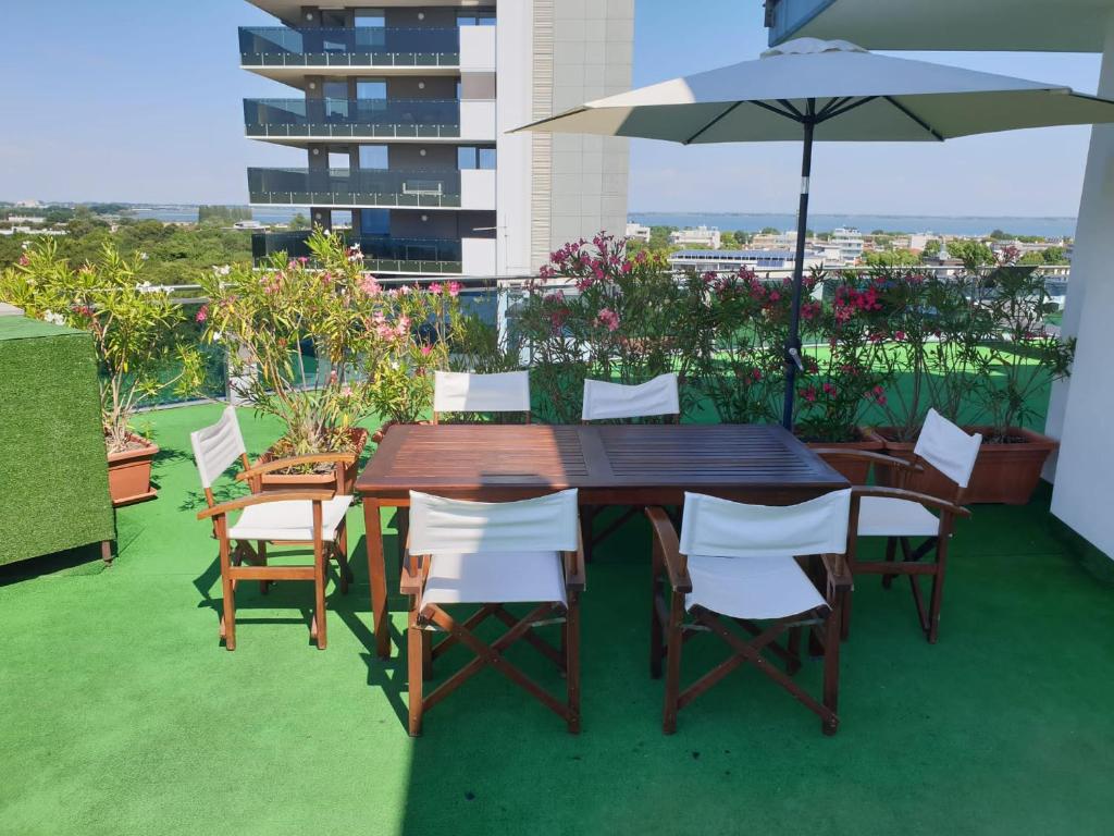une table et des chaises en bois avec un parasol sur un balcon dans l'établissement Hotel Cristallo, à Lignano Sabbiadoro