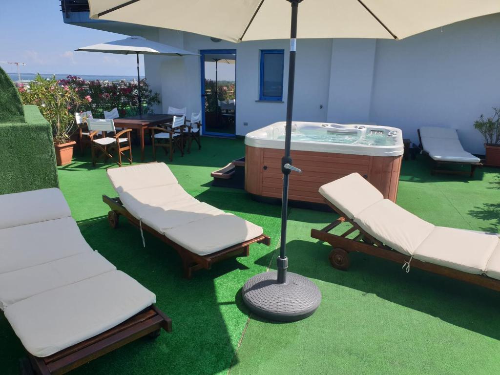 un groupe de chaises et un bain à remous avec un parasol dans l'établissement Hotel Cristallo, à Lignano Sabbiadoro