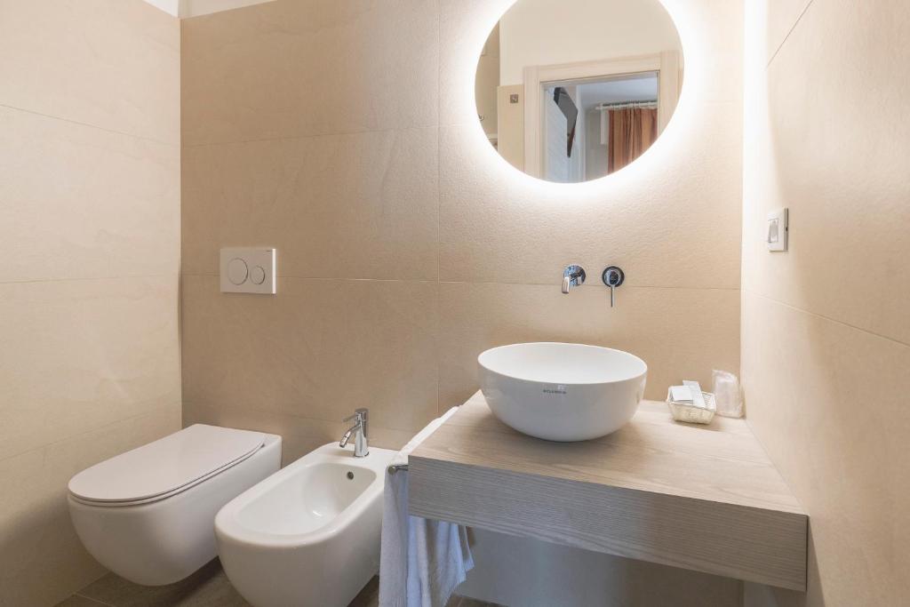 une salle de bain avec un lavabo, des toilettes et un miroir dans l'établissement Hotel Nettuno, à Brenzone