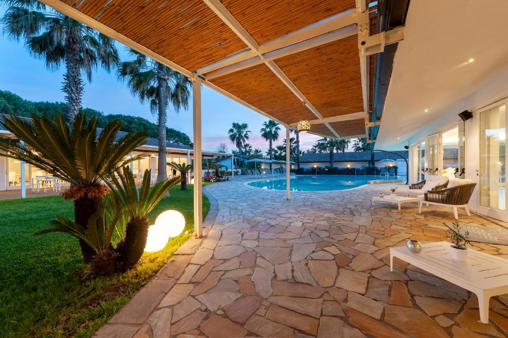 une terrasse avec un sol en pierre et une piscine dans l'établissement Paestum Inn Beach Resort, à Paestum