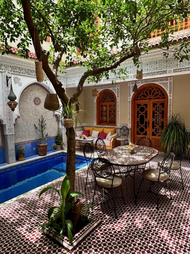 un patio avec une table et des chaises sous un arbre dans l'établissement RIAD SHAJARA, à Marrakech
