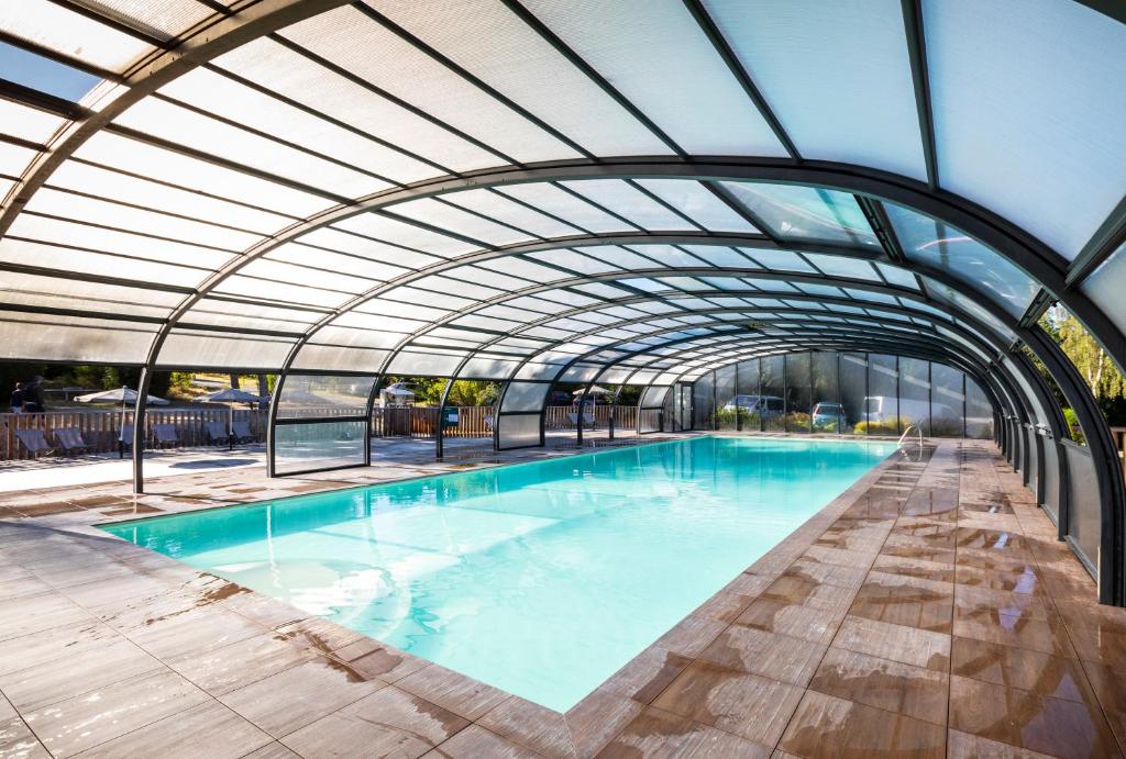 une piscine intérieure avec un plafond en verre dans l'établissement Huttopia Lac de la Siauve, à Lanobre