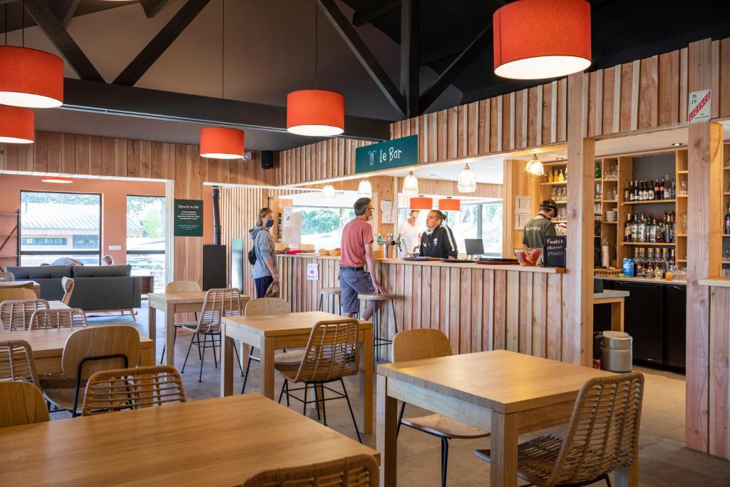 un restaurant avec des tables et des personnes debout à un comptoir dans l'établissement Huttopia Lac de la Siauve, à Lanobre
