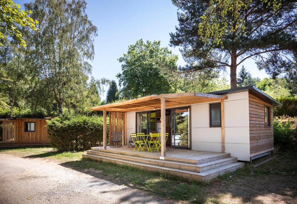 une petite maison avec un porche et une terrasse dans l'établissement Huttopia Lac de la Siauve, à Lanobre