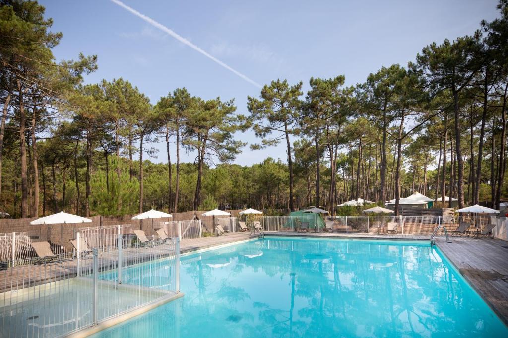 une grande piscine avec chaises et parasols dans l'établissement Huttopia Lac de Carcans, à Carcans