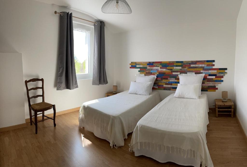 une chambre avec deux lits et une chaise et une fenêtre dans l'établissement Le Grand Gîte, à Pellegrue