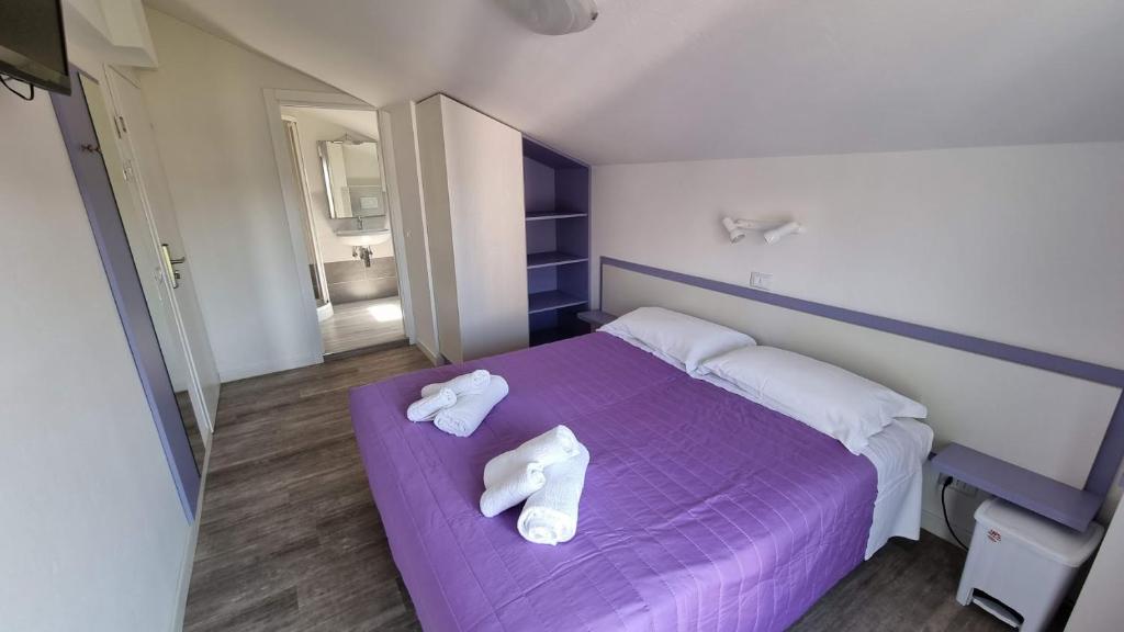 - une chambre avec 2 serviettes sur un lit violet dans l'établissement Hotel Canoa, à Cervia