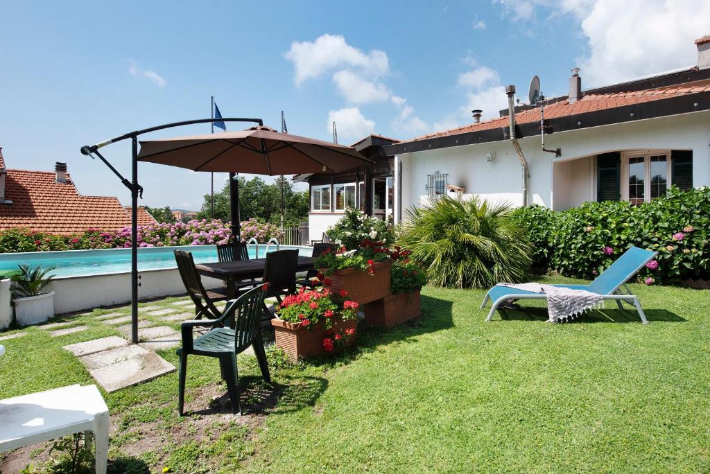 un patio avec un parasol, une table et des chaises dans l'établissement Barcollo House - Piscina nel verde, à Stella
