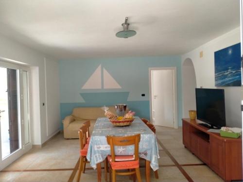 un salon avec une table avec des chaises et une télévision dans l'établissement Vele del Pizzo - piscina, à Gallipoli