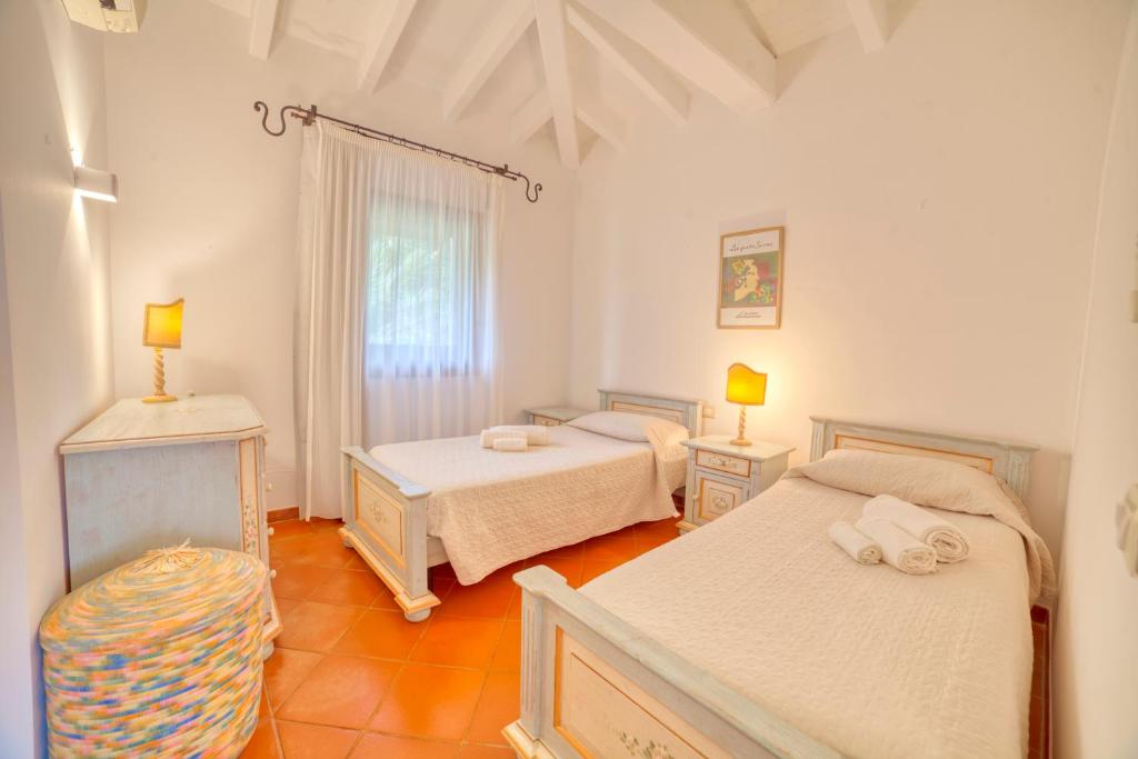 - une chambre avec deux lits et une table avec deux lampes dans l'établissement Villa Hibiscus Stintino, à Stintino