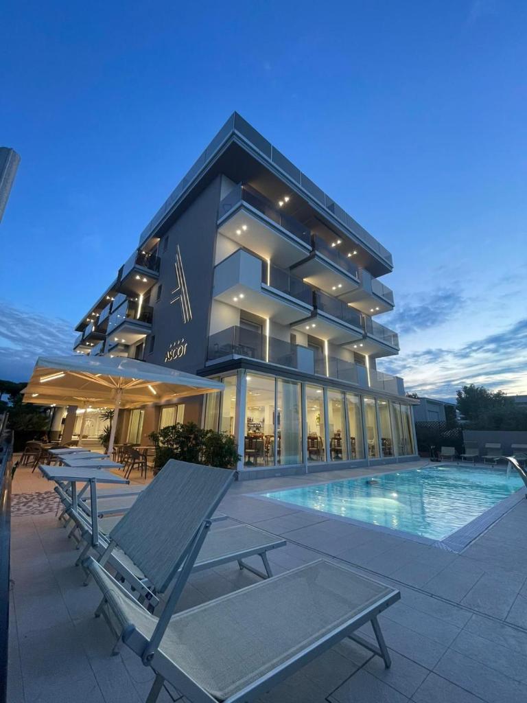 un bâtiment avec une piscine devant dans l'établissement Hotel Ascot Riccione, à Riccione