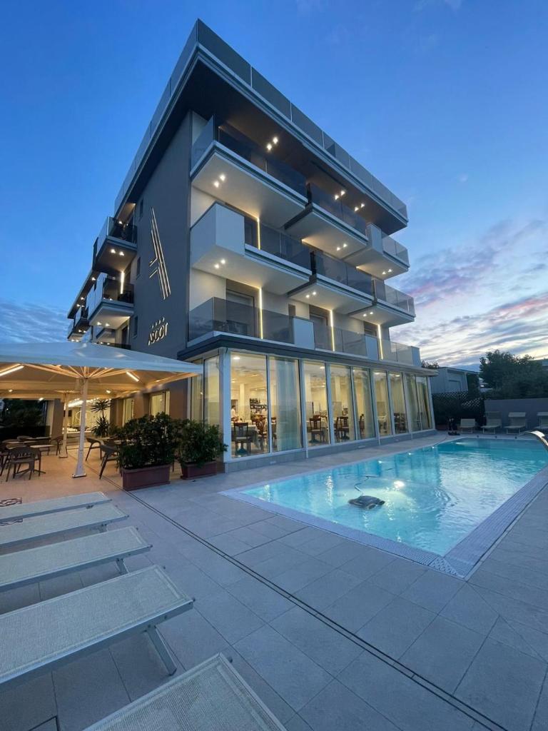 un grand bâtiment avec une piscine devant dans l'établissement Hotel Ascot Riccione, à Riccione