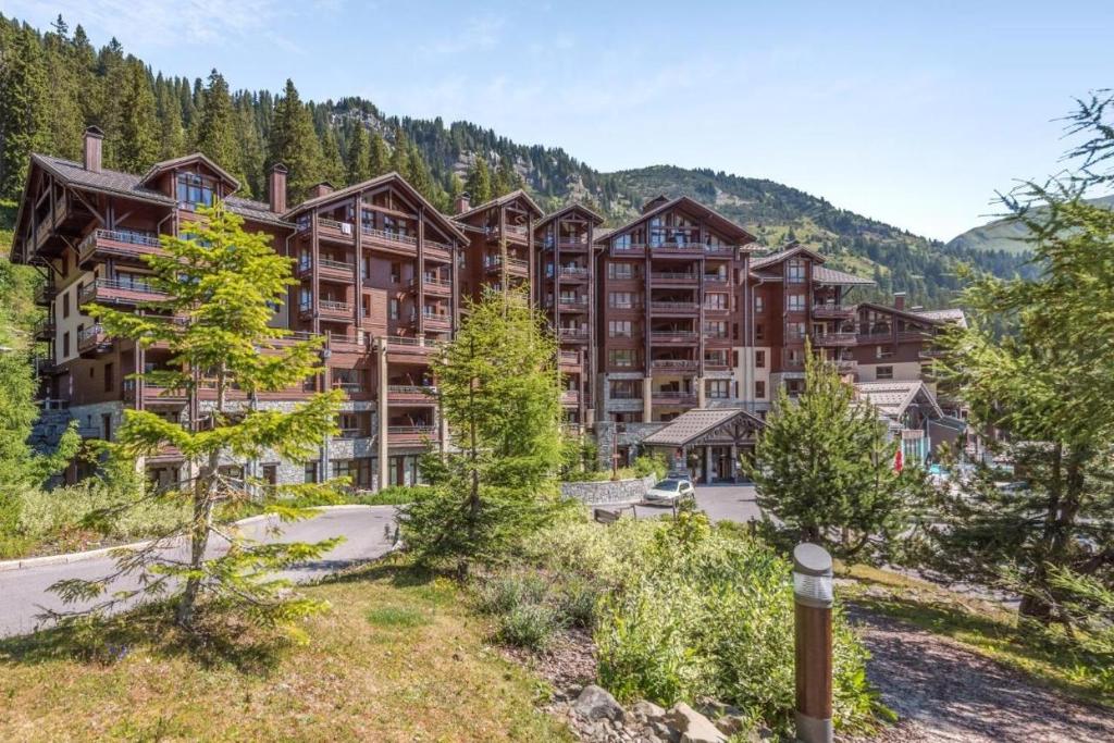 un grand immeuble d'appartements dans les montagnes avec des arbres dans l'établissement Appartement Premium en pleine nature à Flaine, 8 à 10 personnes - Piscine extérieure chauffée, jacuzzi, sauna, hammam et salle de sport, à Flaine