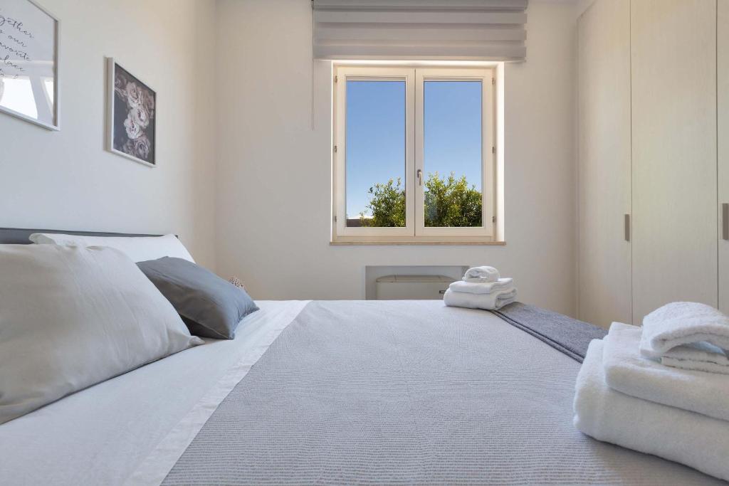 une chambre avec un grand lit blanc avec une fenêtre dans l'établissement Villa Eva by Perle di Puglia, à San Michele Salentino