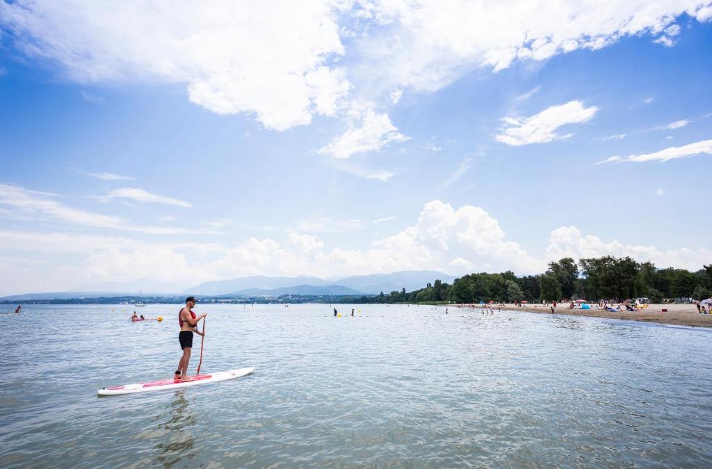 Un homme est debout sur une planche de paddle dans l'eau dans l'établissement Camping La Pinède, à Excenevex
