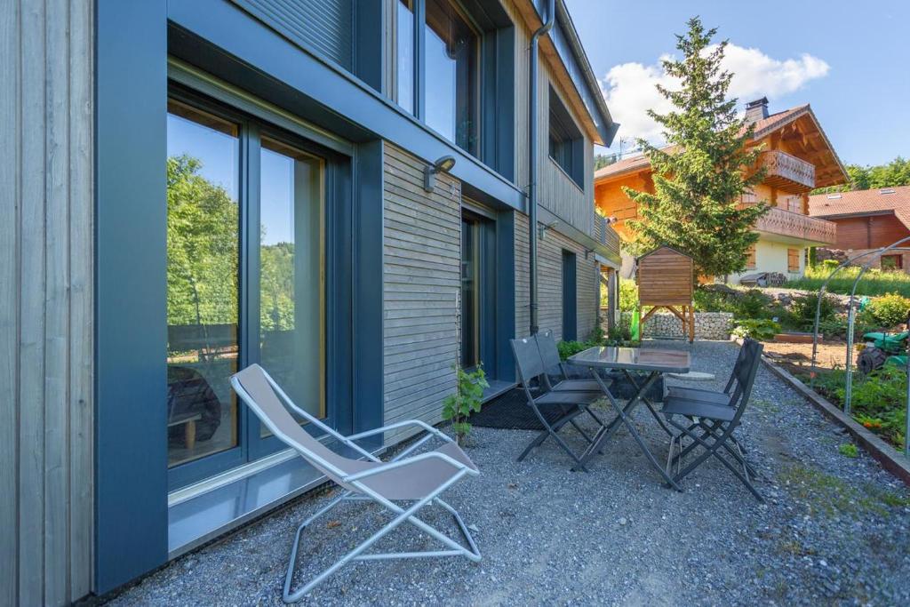 un patio avec des chaises et une table à côté d'un bâtiment dans l'établissement Eco-gite Dans Chalet Neuf Au Pied, à Habère-Poche 13 autres photos