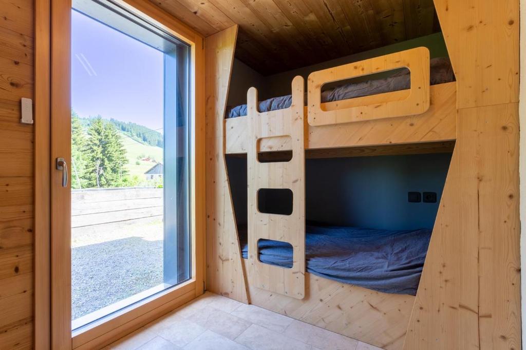 Ce lit superposé se trouve dans une petite maison dotée d'une fenêtre. dans l'établissement Eco-gite Dans Chalet Neuf Au Pied, à Habère-Poche