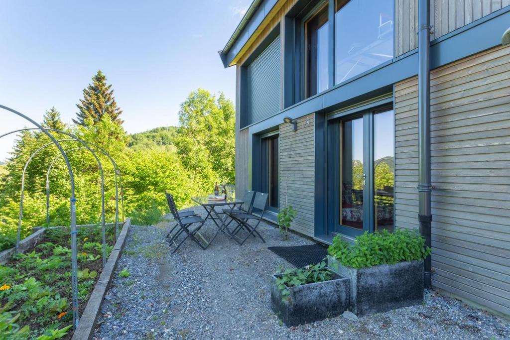 un patio avec une table et des chaises à côté d'un bâtiment dans l'établissement Eco-gite Dans Chalet Neuf Au Pied, à Habère-Poche