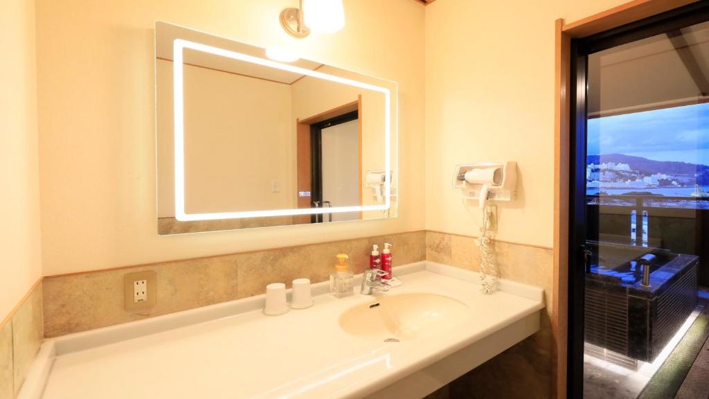 une salle de bain avec un lavabo et un grand miroir dans l'établissement Syukaen Yunohanazen, à Atami