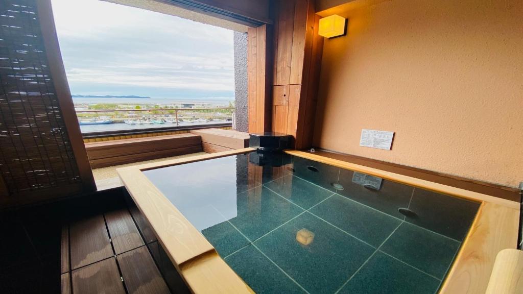 La salle de bains est pourvue d'une baignoire et d'une grande fenêtre. dans l'établissement Syukaen Yunohanazen, à Atami