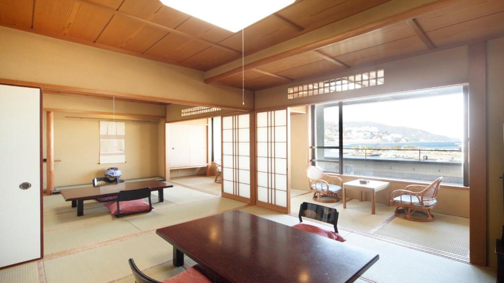 un salon avec une table et une grande fenêtre dans l'établissement Syukaen Yunohanazen, à Atami