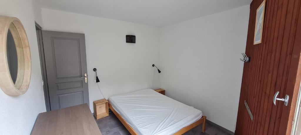 Cette petite chambre comprend un petit lit et une porte. dans l'établissement Un petit coin de paradis, à Villard-de-Lans