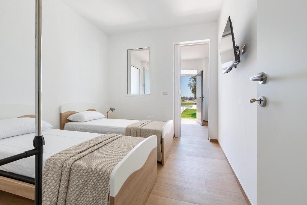 deux lits dans une chambre aux murs blancs dans l'établissement Villa La Quiete by BarbarHouse, à Copertino