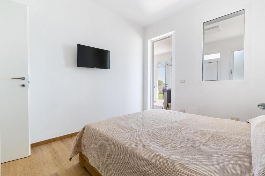 une chambre blanche avec un lit et une télévision au mur dans l'établissement Villa La Quiete by BarbarHouse, à Copertino