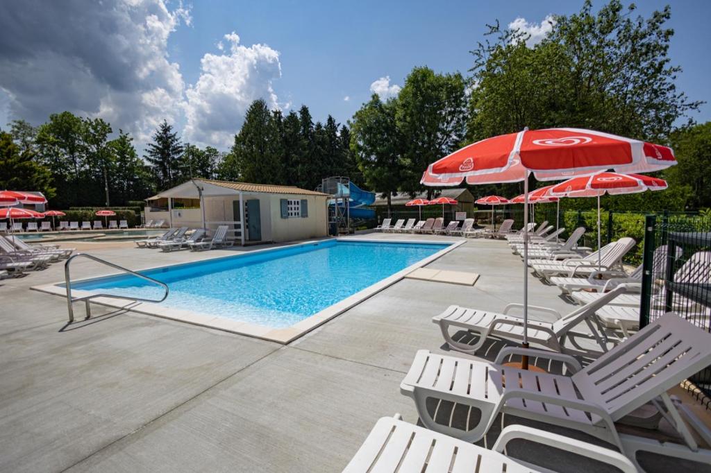 une piscine avec chaises et parasols dans l'établissement Camping Country Park Touquin - Site Officiel - Next to Disneyland Paris, à Touquin