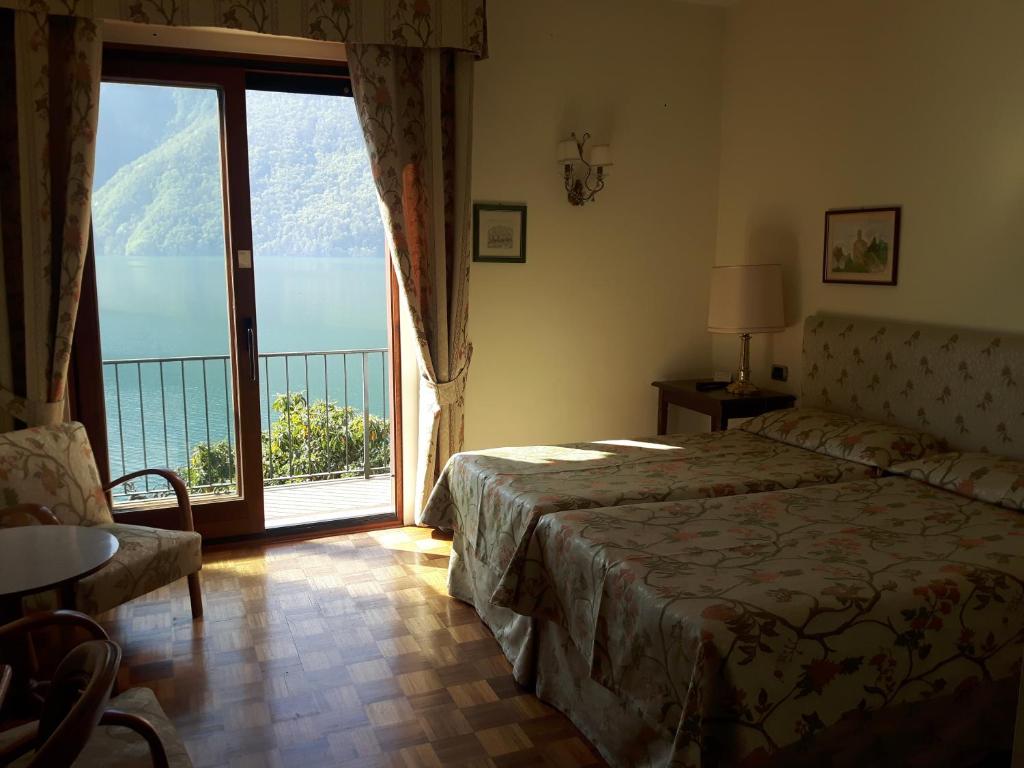 une chambre avec un lit et une grande fenêtre dans l'établissement Hotel Stella D'Italia, à Valsolda