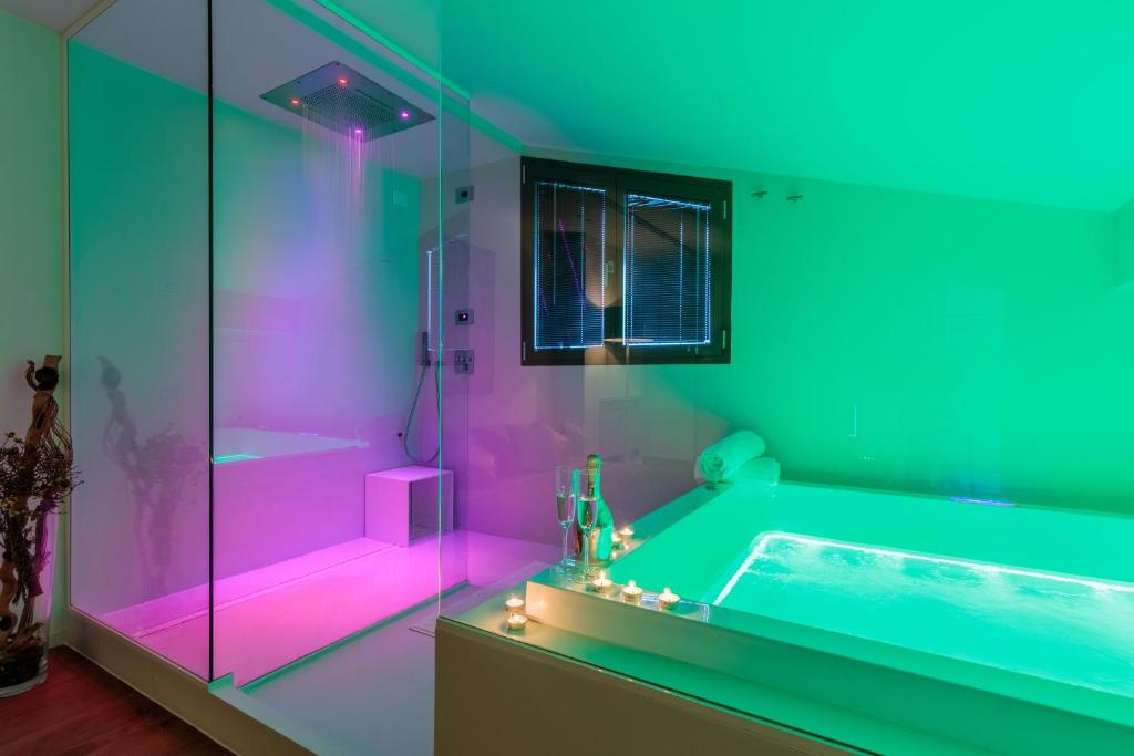 une salle de bain avec une baignoire avec un éclairage rose et vert dans l'établissement LUXURY VILLA RUBIN with Jacuzzi POOL GYM & SPA near Venice and Padua, à Arzergrande