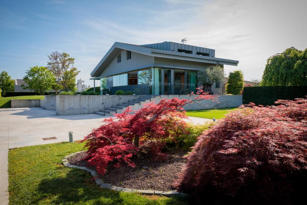 une maison avec des buissons rouges devant un bâtiment dans l'établissement LUXURY VILLA RUBIN with Jacuzzi POOL GYM & SPA near Venice and Padua, à Arzergrande
