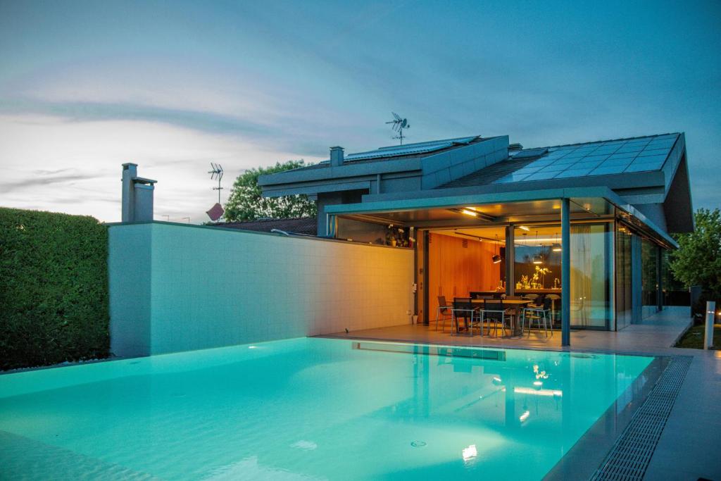 une maison avec une piscine devant une maison dans l'établissement LUXURY VILLA RUBIN with Jacuzzi POOL GYM & SPA near Venice and Padua, à Arzergrande