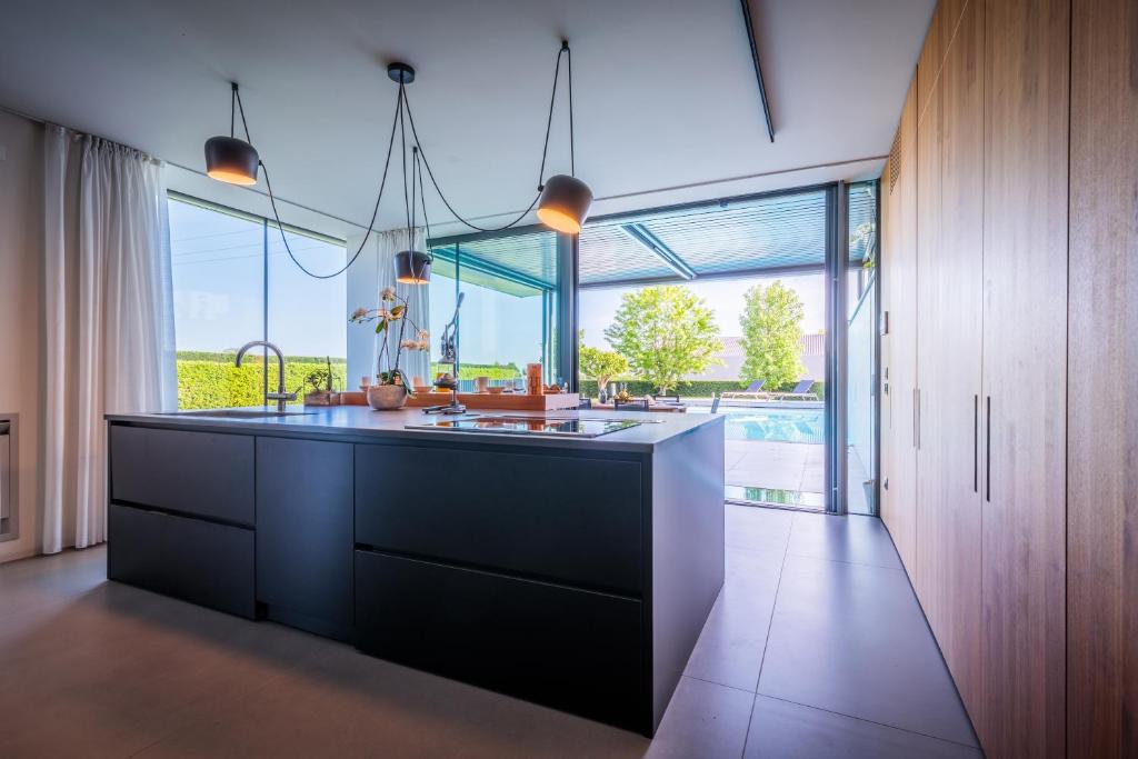 une cuisine avec une grande île et une grande fenêtre dans l'établissement LUXURY VILLA RUBIN with Jacuzzi POOL GYM & SPA near Venice and Padua, à Arzergrande