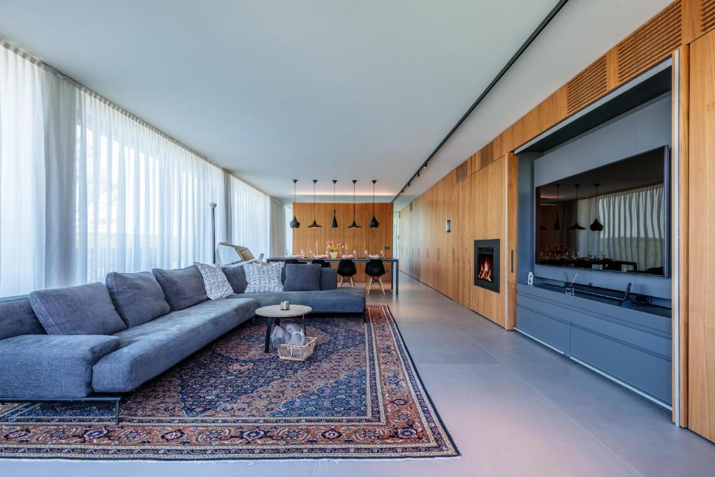 un salon avec un canapé bleu et un tapis dans l'établissement LUXURY VILLA RUBIN with Jacuzzi POOL GYM & SPA near Venice and Padua, à Arzergrande