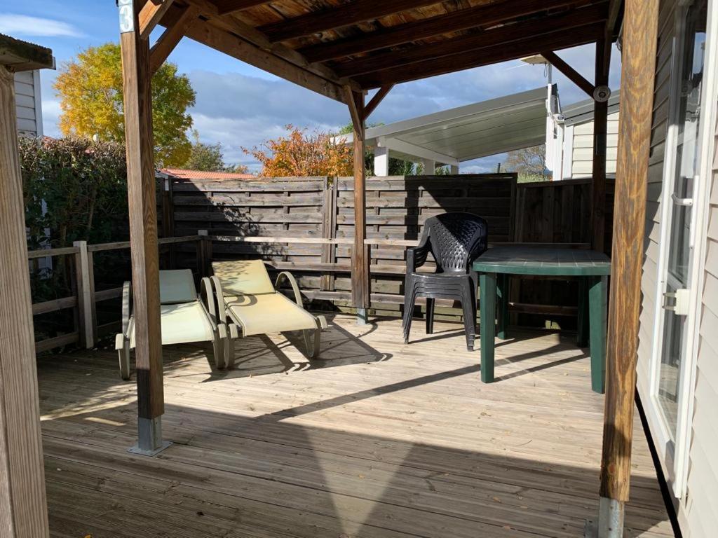 une terrasse en bois avec une table et des chaises. dans l'établissement Mobilhome dans résidence, à Ruoms