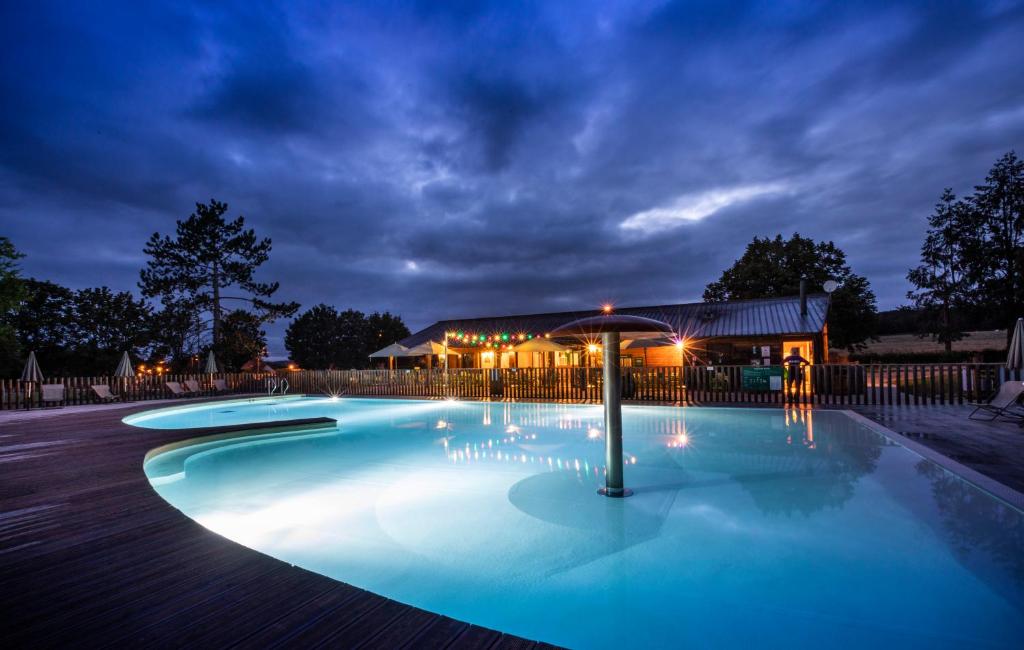 - une piscine avec un parasol en face d'un bâtiment dans l'établissement Huttopia Etang Fouché, à Arnay-le-Duc