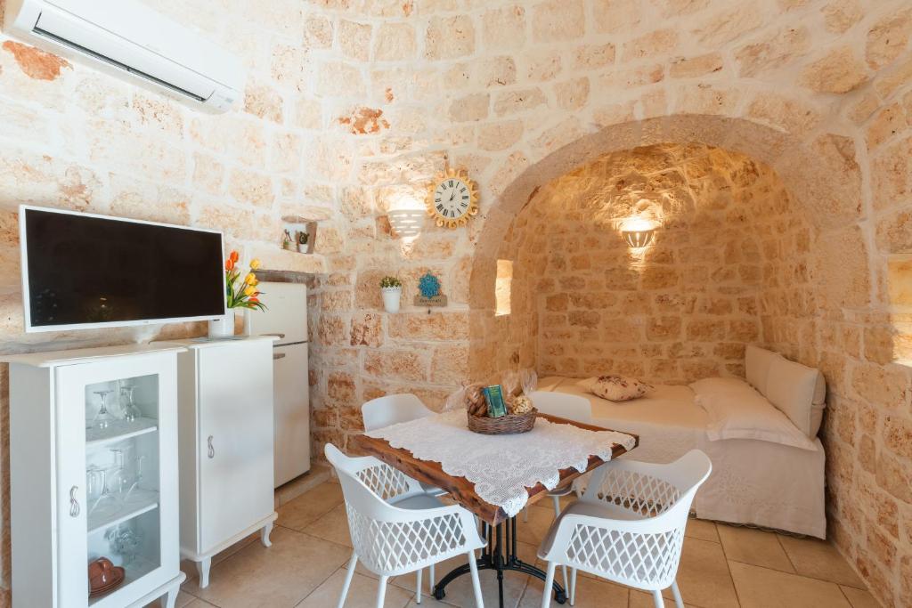 un salon avec une table, des chaises et une télévision dans l'établissement Trullo Milù, à San Michele Salentino